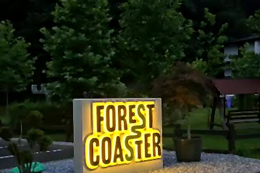 Firma luminoasă Forest Coaster, la intrare, în amurg